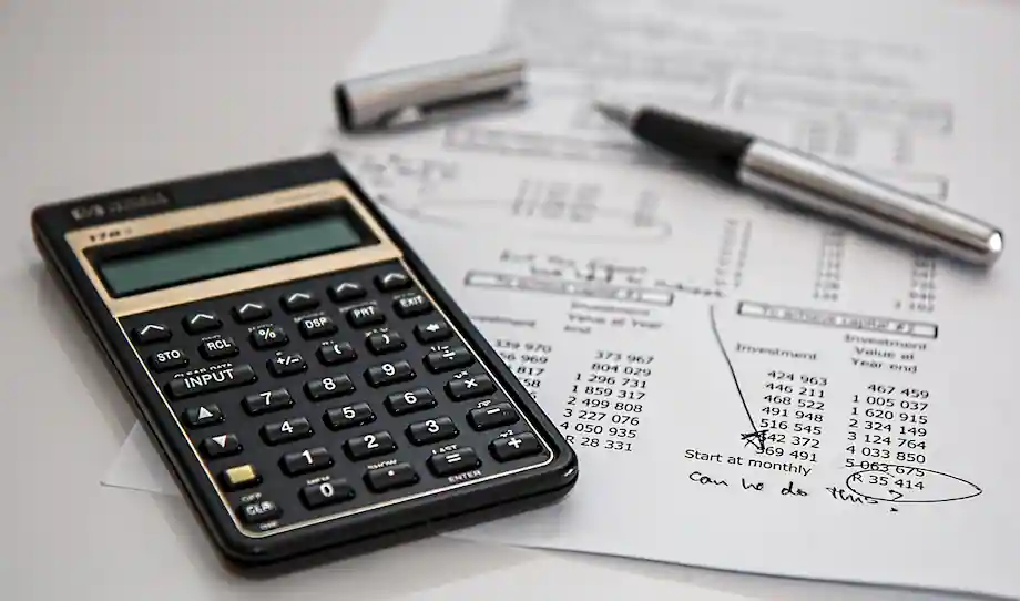 Calculadora y pluma sobre un documento de un balance financiero